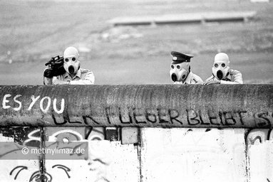 BERLIN (West), DEUTSCHLAND - 21.06.1988: Mit Gasmasken ausgerüstet blicken DDR-Grenzsoldaten über die Mauer am Lenné-Dreieck, Potsdamer Platz von Ost- nach West-Berlin.